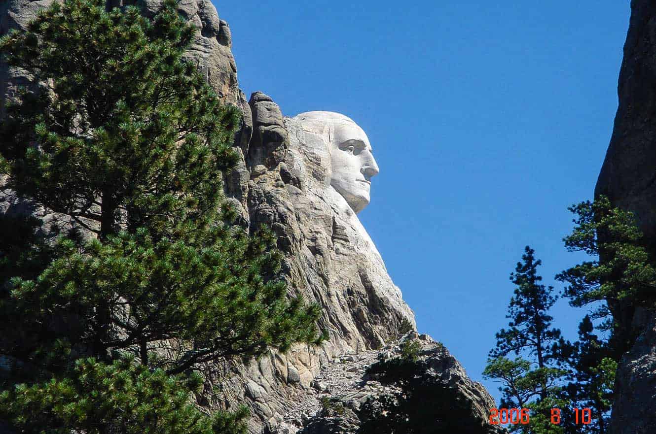 George Washington's profile at Mount Rushmore, seen from the side and framed by pine trees