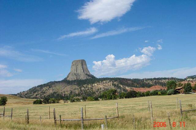 Devils Tower rising above a fenced pasture