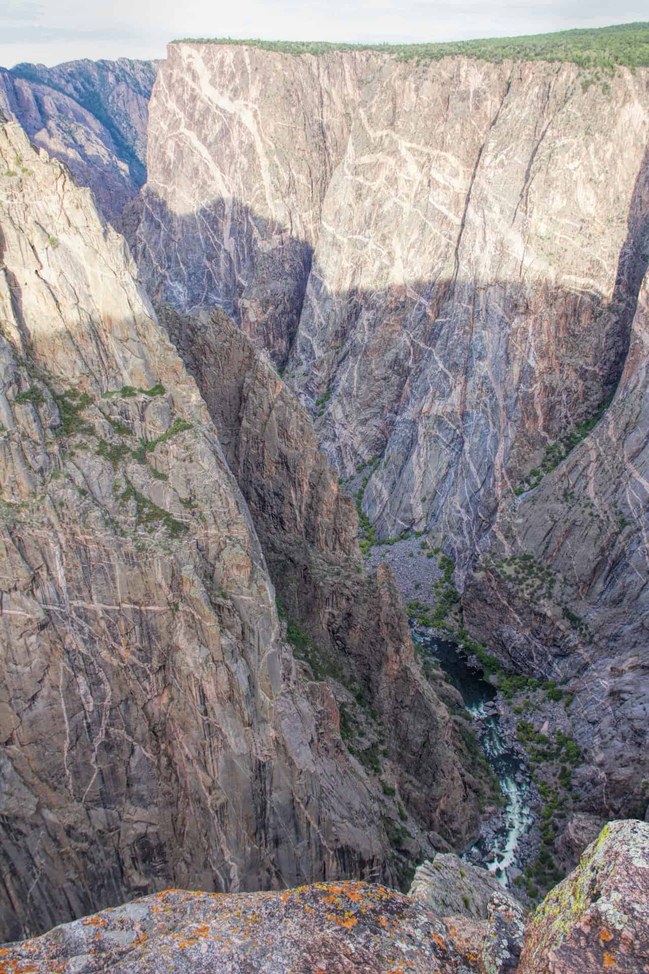 A dramatic vertical view straight down into the Black Canyon of the Gunnison, with the river visible far below