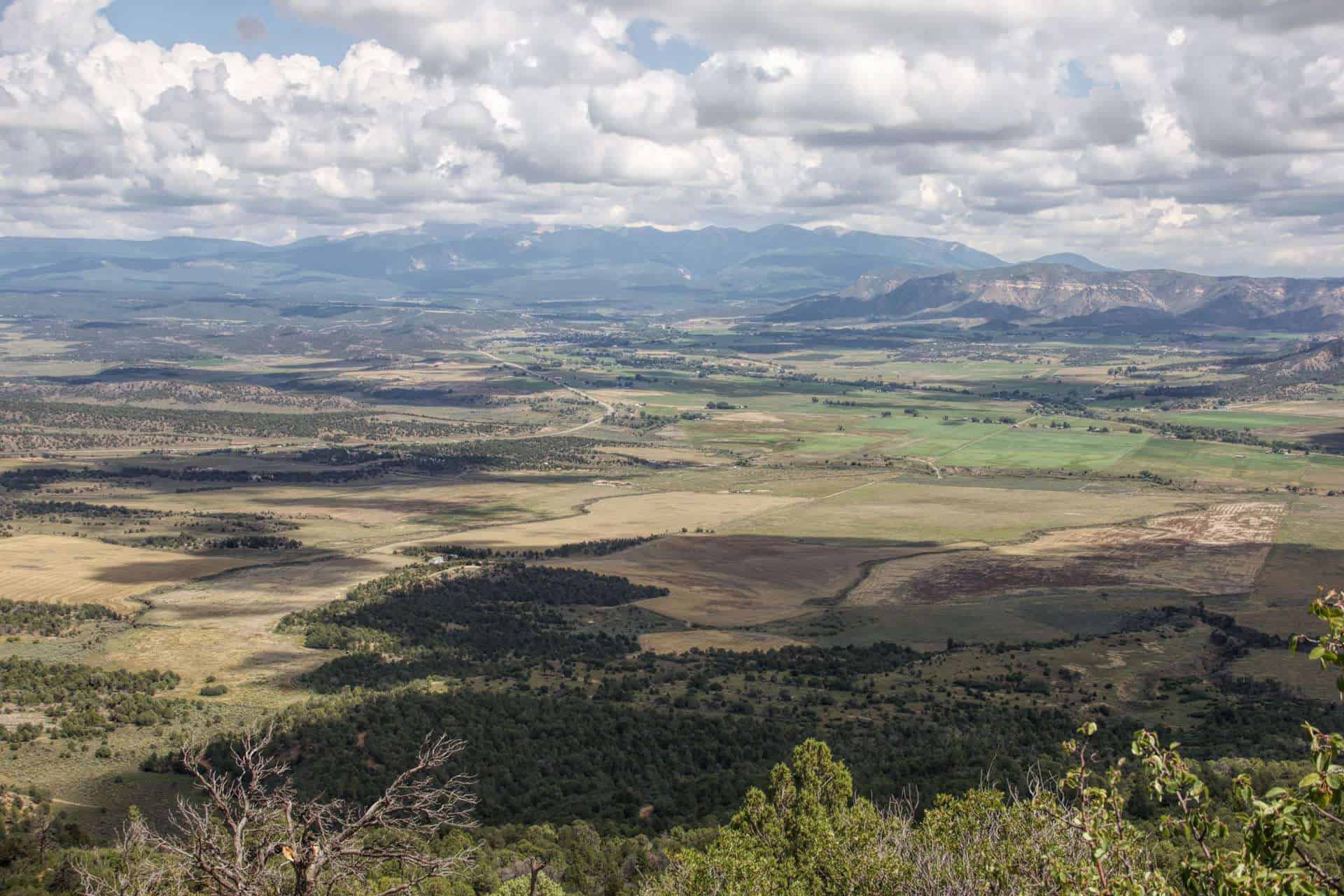A wide valley view from Wetherill Mesa overlooking farmland and distant mountains under a cloudy sky