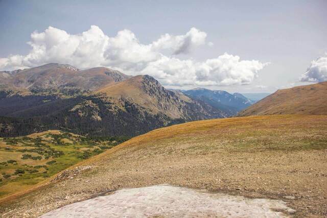 Rocky alpine tundra along Trail Ridge Road with a winding road visible below distant peaks
