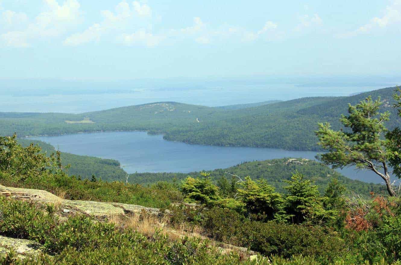 A view of a forested lake from a granite summit in Acadia National Park