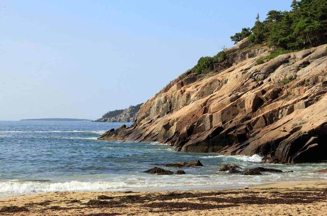 The pink granite cliffs and rocky shoreline of Sand Beach in Acadia National Park