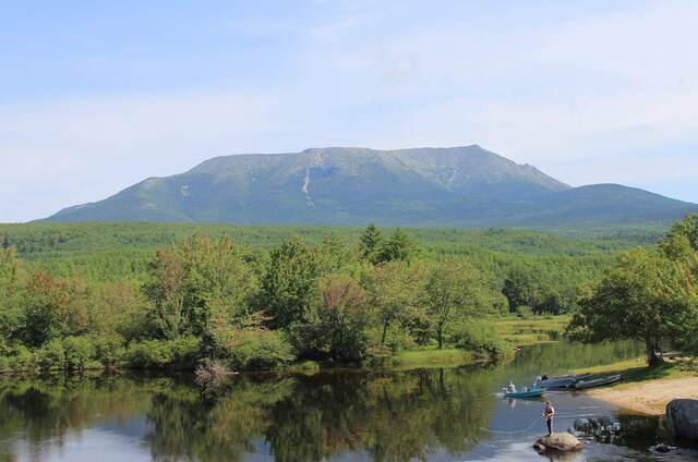 Mount Katahdin rising above the Penobscot River, with anglers fishing from the bank