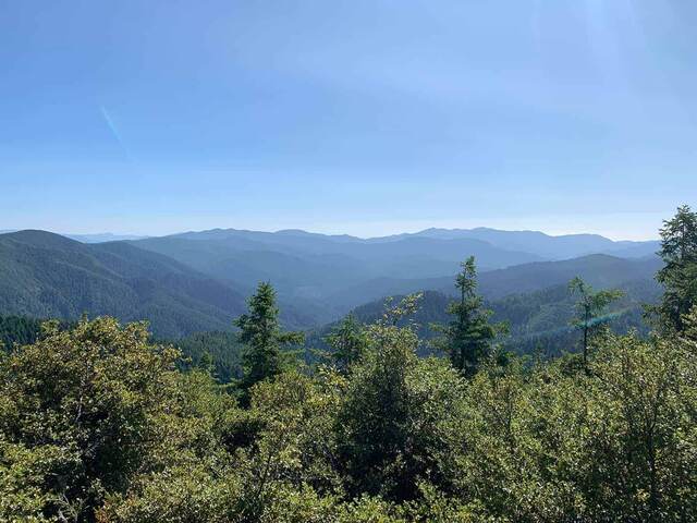 A hazy panoramic view of forested mountain ridgelines fading into the distance