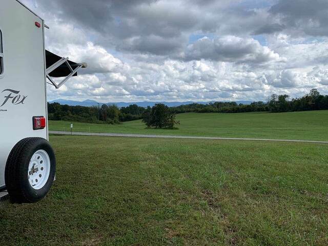 The RV parked in a grassy field at Marceline Vineyards, mountains in the distance