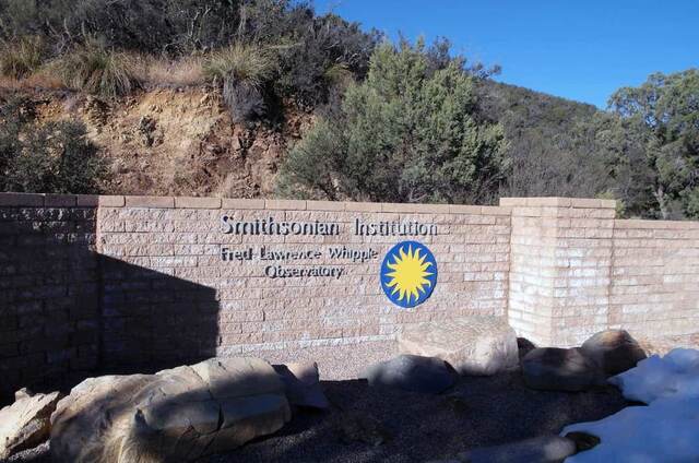 The stone entrance sign for the Smithsonian Institution's Fred Lawrence Whipple Observatory, with patches of snow on the ground