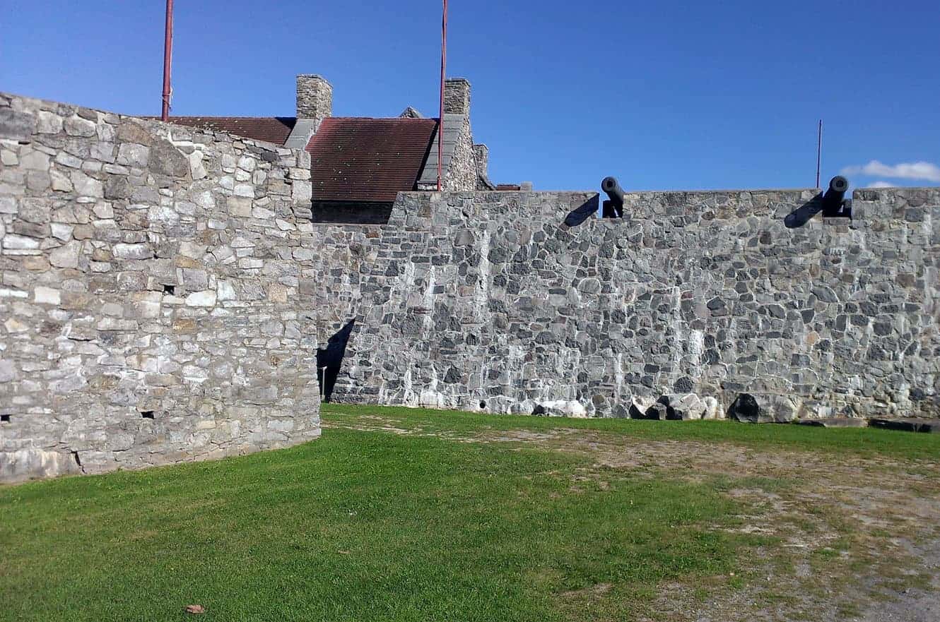 The stone ramparts of Fort Ticonderoga lined with cannons, with the barracks roofline behind