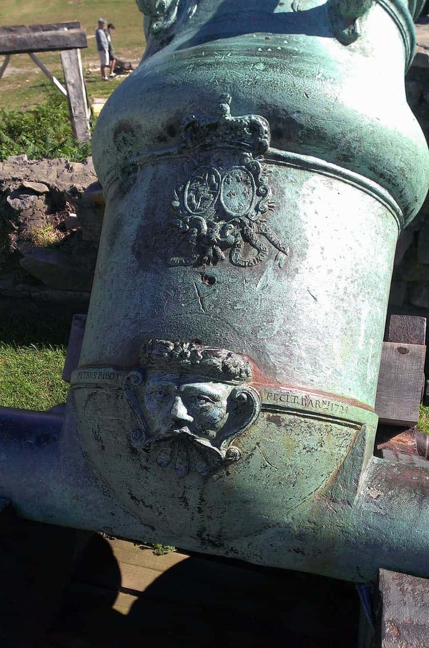 A close-up of an ornate royal crest and maker's engravings on one of the fort's bronze cannons