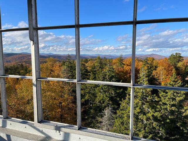 Rolling hills of fall foliage seen through the windows of an old fire tower