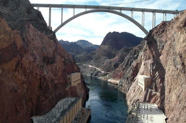 The Mike O'Callaghan-Pat Tillman Memorial Bridge arching over the Colorado River canyon downstream of Hoover Dam, with the powerhouses visible on either bank