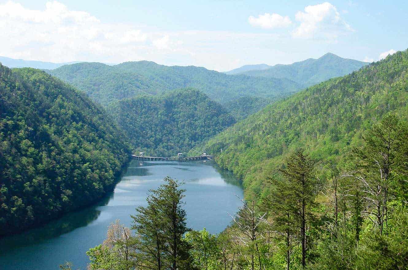A dam spanning a river gorge in the Tennessee mountains, seen from a forested overlook