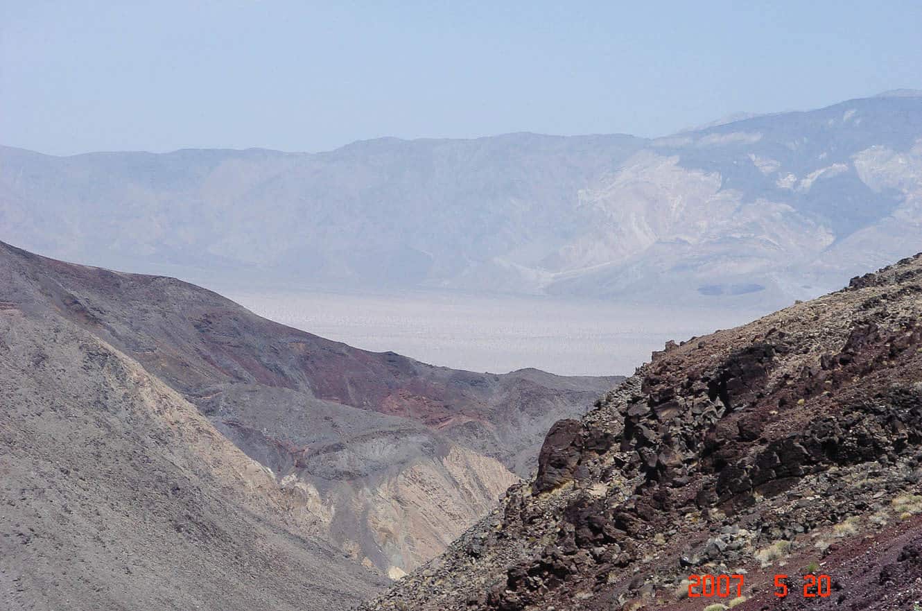 Colorful badlands and hazy mountains viewed from a ridge above Death Valley