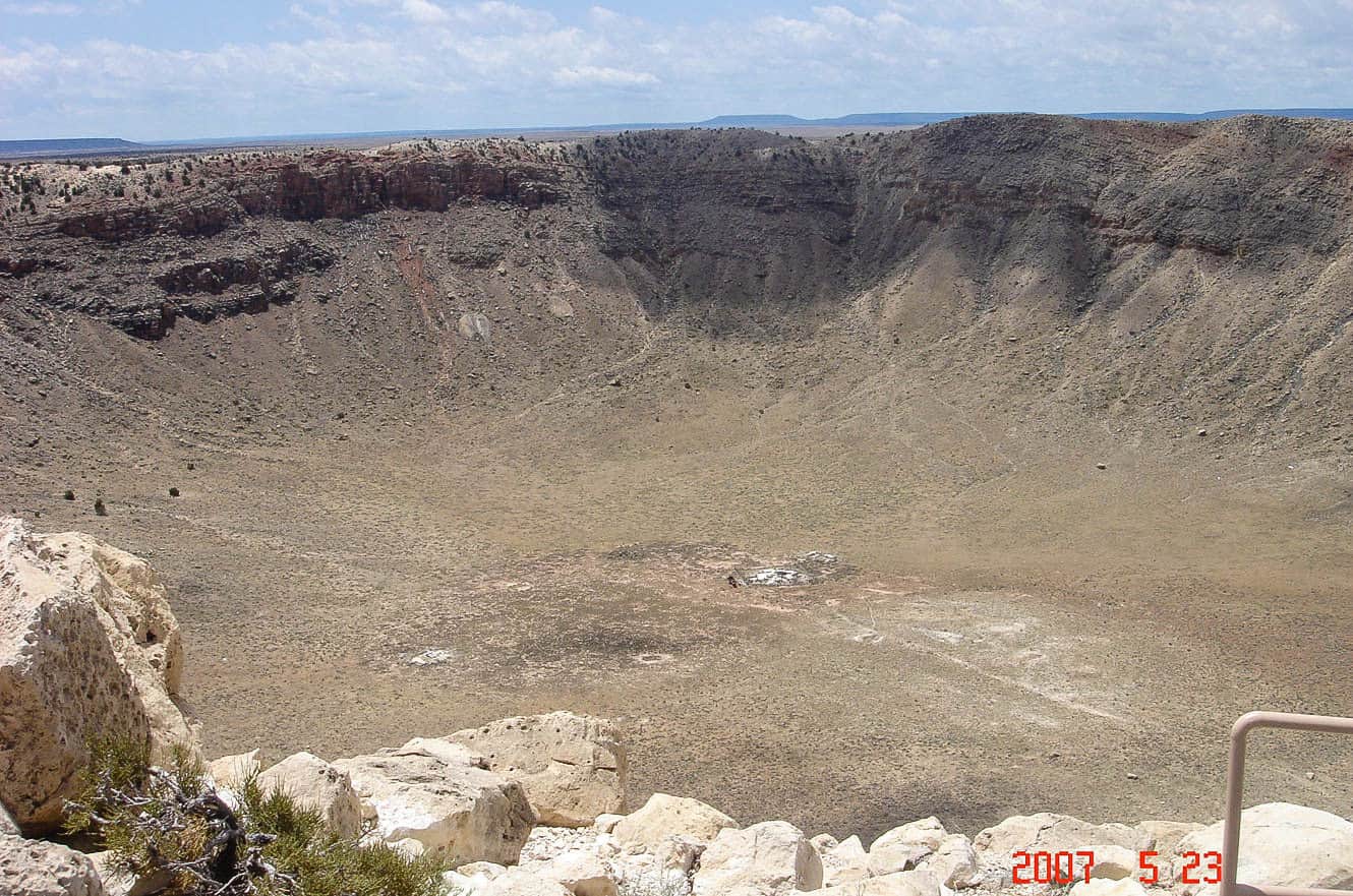 The vast crater floor of Meteor Crater, ringed by layered rock walls