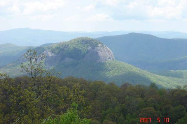 A distant view of Looking Glass Rock, its bare granite face rising above the forested ridgeline