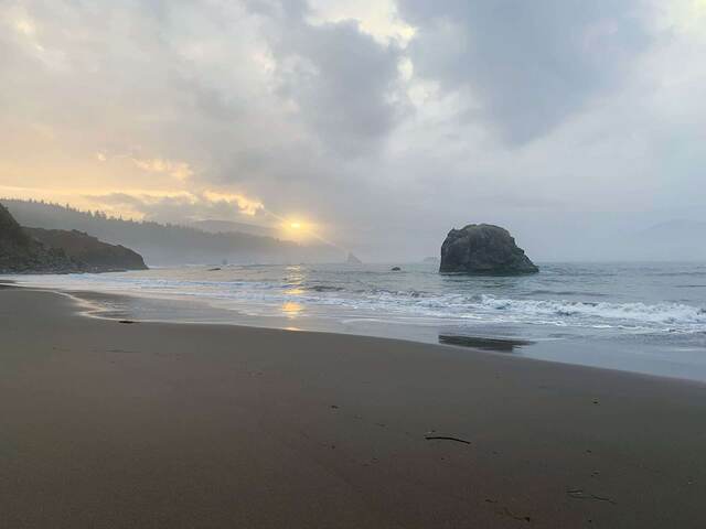 A misty sunset over a rock formation on an Oregon beach