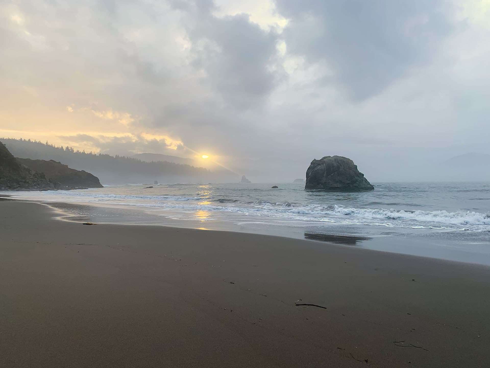 A misty sunset over a rock formation on an Oregon beach
