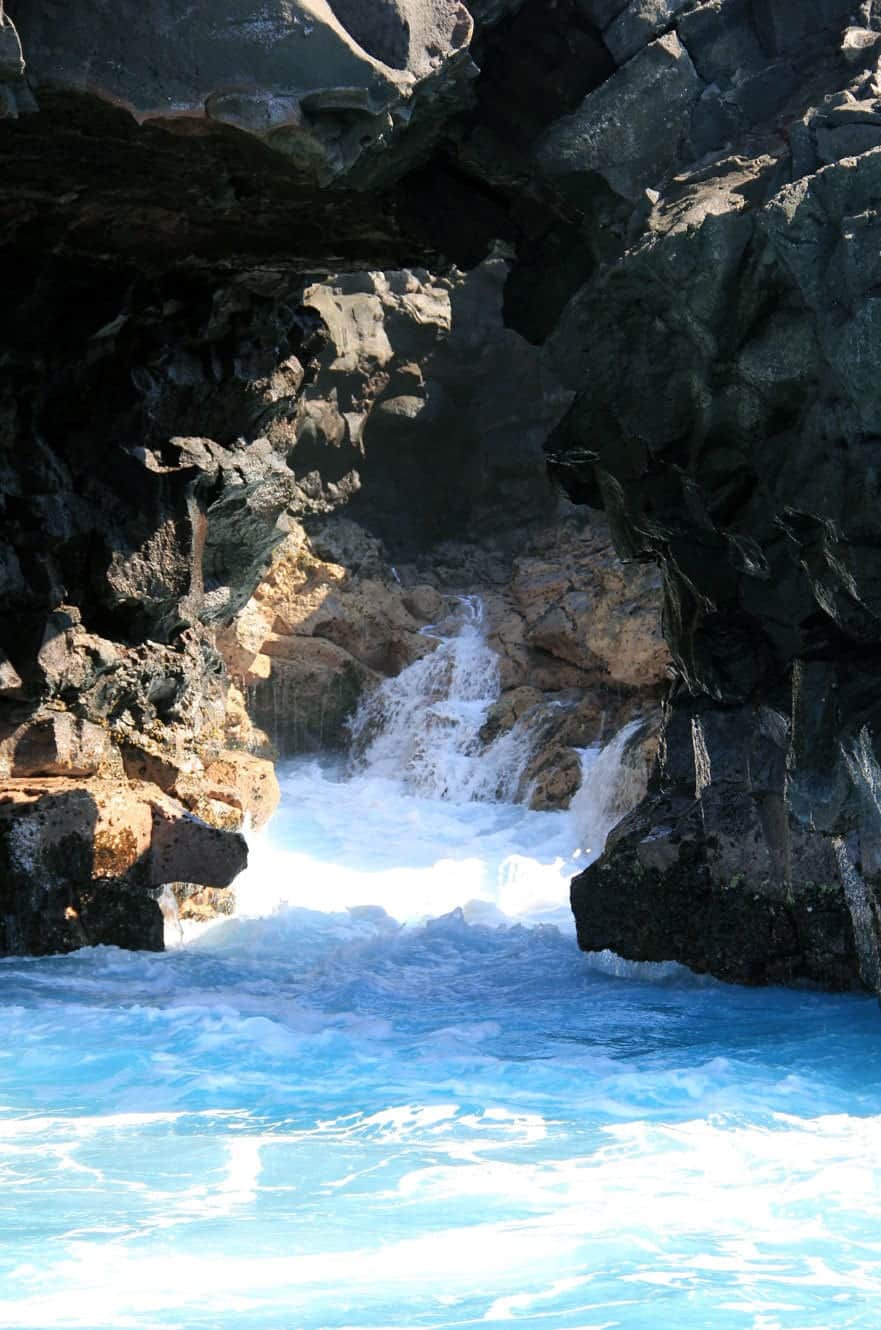 Waves surging through a narrow sea cave, spray catching the light