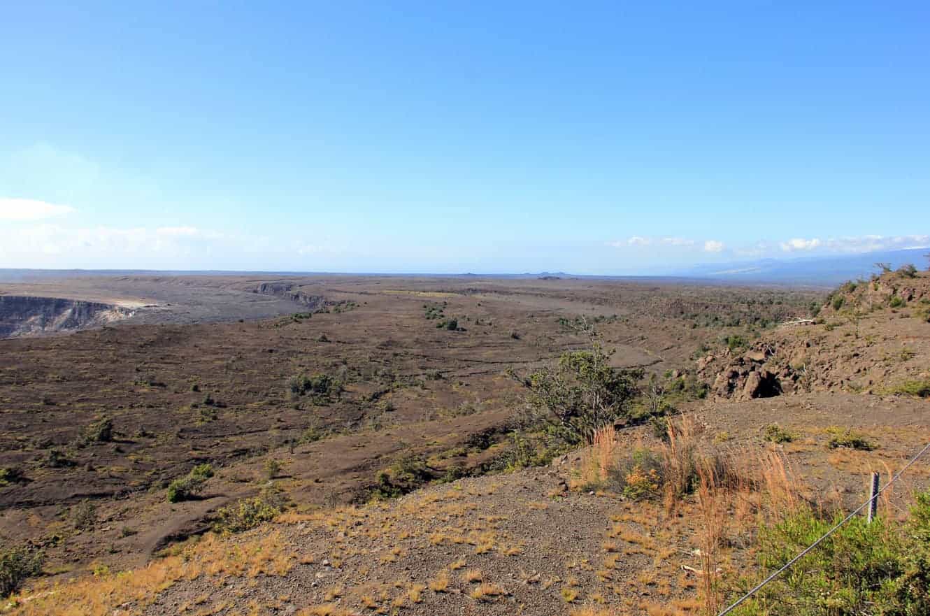A panoramic view of the Kilauea caldera with distant hills and forest