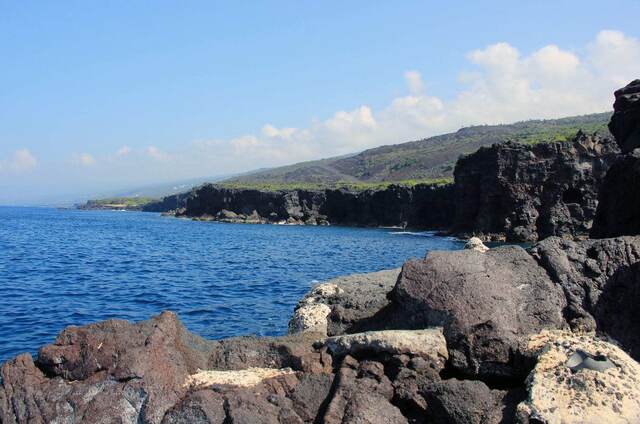 Lava cliffs and calm blue ocean along the coastline where the snorkeling took place