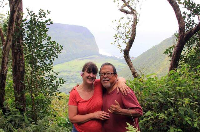 Hillary and her riding guide Kevin posing together with the Waipio Valley overlook behind them