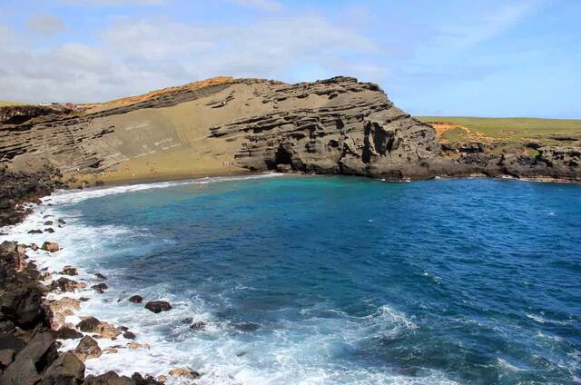 A sweeping view of Papakolea Green Sand Beach cove with its cinder cone cliffs and turquoise water