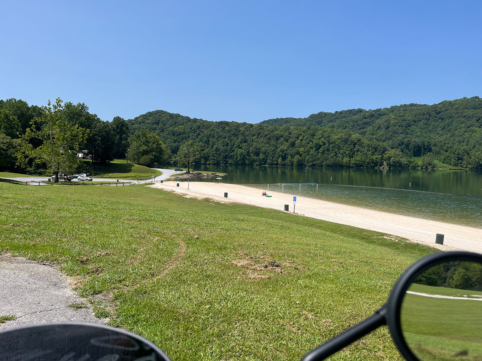 Gulston Lake's sandy beach, seen past the motorcycle's mirrors